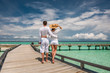 © haveseen - Couple in white on a beach jetty at Maldives
