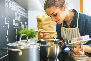 Young woman cooking in her kitchen standing near stove