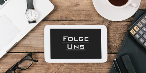 Wall Mural - Folge Uns, German text for Follow Us on screen of tablet computer at office desk