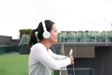 Young Asian Woman Listening Music In Headphones At Rooftop Of The Building