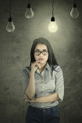 Wall Mural - Pensive businesswoman under a bright bulb