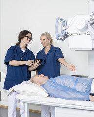 Radiologist Gesturing Towards Patient While Colleague Holding Di