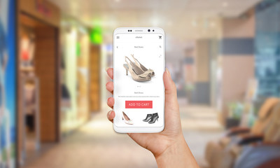 Poster - Online shop on mobile phone display. Modern white smart phone with round edges in girl hand. Shopping mall in background.