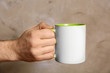 Male hand holding white cup on blurred background