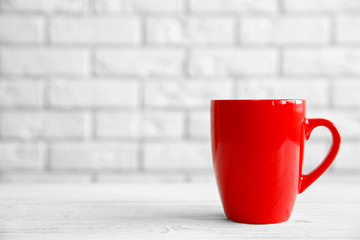 Wall Mural - Red cup on table against white brick wall background