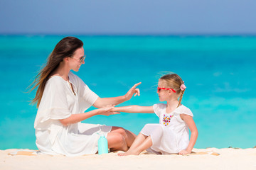 Wall Mural - Ypung mother applying sun cream to daughter nose