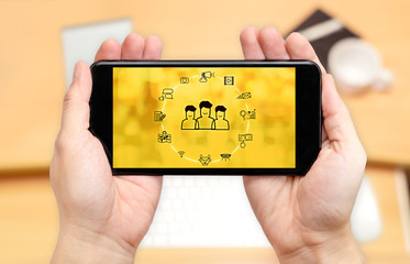 Poster - Watching two hand holding mobile phone with digital advertise marketing features on screen and blur desk office background,Digital content concept