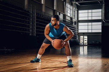 Wall Mural - Professional basketball player in an action in basketball field.