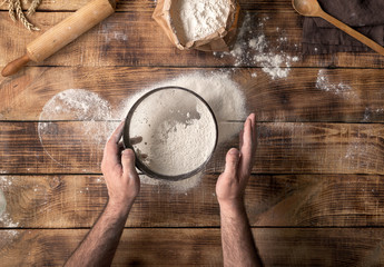 Canvas Print - Man sifted flour on the wooden table