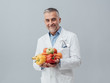 © stokkete - Smiling nutritionist holding fresh vegetables and fruit