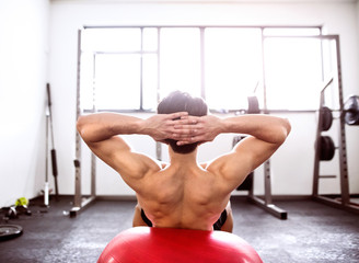 Fit hispanic man in gym training, working abs, doing crunches