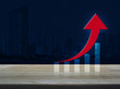 © grapestock - Red arrow with graph on wooden table over modern office city tower background, Success business concept