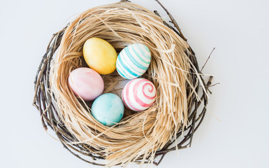 Colorful Easter Eggs isolated on the white background with nest and wreath. Selective focus.