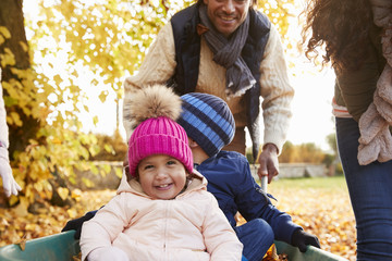 Wall Mural - Father In Autumn Garden Gives Children Ride In Wheelbarrow