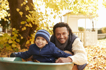 Wall Mural - Father In Autumn Garden Gives Son Ride In Wheelbarrow