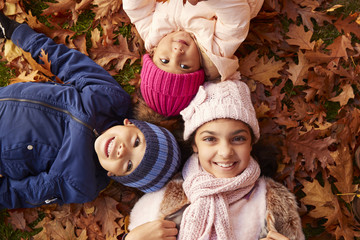 Wall Mural - Overhead Portrait Of Three Children Lying In Autumn Leaves