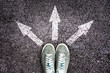 Sneakers shoes and arrows pointing in different directions on asphalt floor, life and studies choice for young people concept