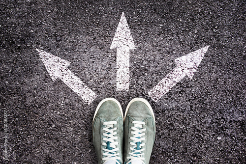 Fotografía Shoes and arrows pointing in different directions on asphalt floor, choice in li
