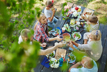 Adults Toasting With Wineglasses By Served Table During Family Dinner
