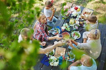 Adults toasting with wineglasses by served table during family dinner