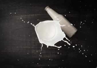 Wall Mural - Milk splash and bottle milk on dark wooden table,Top view