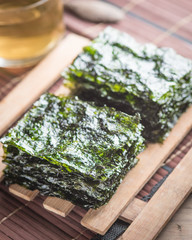 Canvas Print - Nori sheets with tea in a glass on wood