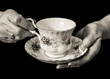 English lady's hands holding a teacup and saucer. Monochrome.