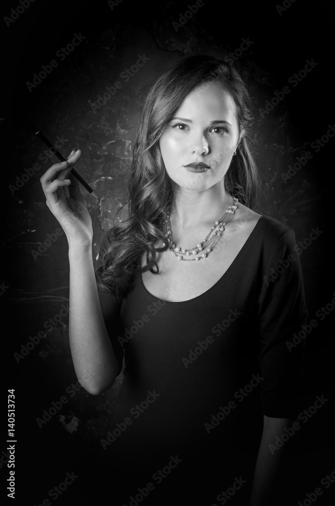 Noir film style woman in dress holding cigarette standing back to camera.  Female posing with gun. Black and white photography. Old fashion photo  Stock Photo