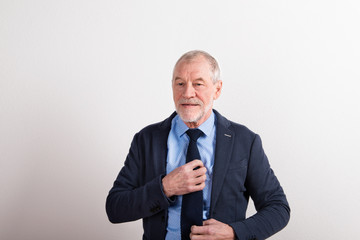 Wall Mural - Senior man wearing blue shirt, jacket and tie, studio shot.