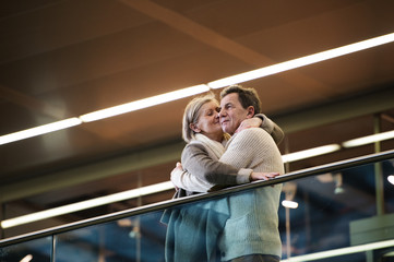 Senior couple standing at the train station, waiting, kissing