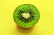 Green kiwi in shape of heart on yellow background