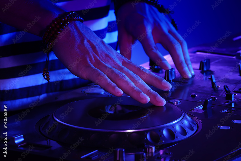 DJ mixing tracks on a mixer in a nightclub