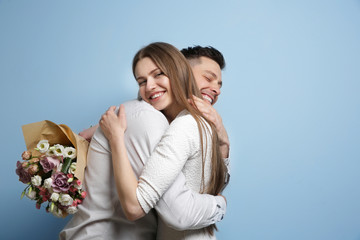 Canvas Print - Happy young couple with bouquet of flowers on light background