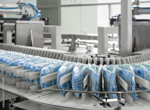 diapers on a conveyor belt closeup. factory and equipment for the