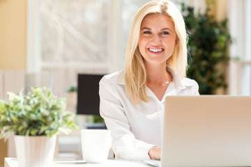 Wall Mural - Happy young woman sitting at her desk