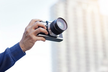 woman holding film camera taking photo in the city