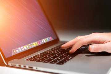 Hand typing on a keyboard of laptop with operating system screen on background