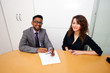© MDBPIXS - Multi-ethnic work colleagues signing paperwork on a table