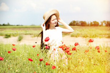 Canvas Print - Beautiful girl with hat in poppy field on sunny summer day