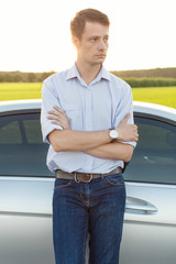 Wall Mural - Young man looking away while standing by car at countryside