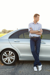 Wall Mural - Full length of young man looking away while standing by car at countryside