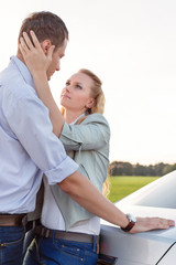 Wall Mural - Side view of romantic young couple by car at countryside