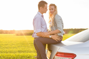 Wall Mural - Side view of romantic young couple by car at countryside