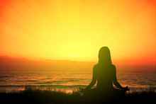 Girl Doing Yoga Meditating In The Beach Sitting On The Grass At Sunset. Empty Copy Space For Editor's Text.