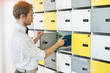 © MDBPIXS - Side view of creative businessman putting files in locker at office