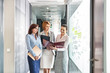 © MDBPIXS - Businesswomen with file folders discussing in office corridor