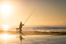 Fishermen With Fishing Rod At Sunrise On Beach