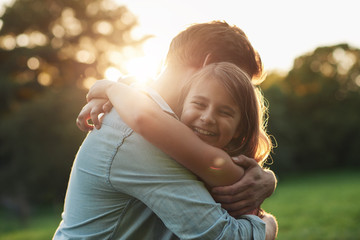 Smiling little girl hugging her father outside