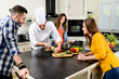 © W PRODUCTION - professional personal chef cook in customer's private kitchen house giving a cooking lesson to young people at home
