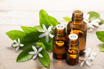 Wall Mural - neroli essential oil in the brown glass bottle, with fresh white neroli flower and green leaves.